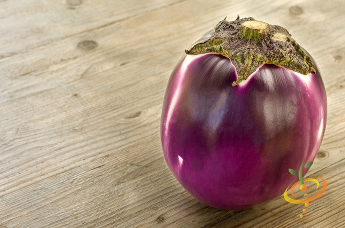Round mauve eggplant (aubergine) with smooth skin on wooden surface, ideal for container gardening and seed starting.