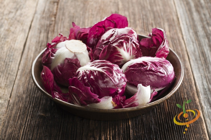 Bowl of Red Acre cabbage heads with deep red and white leaves on wooden surface