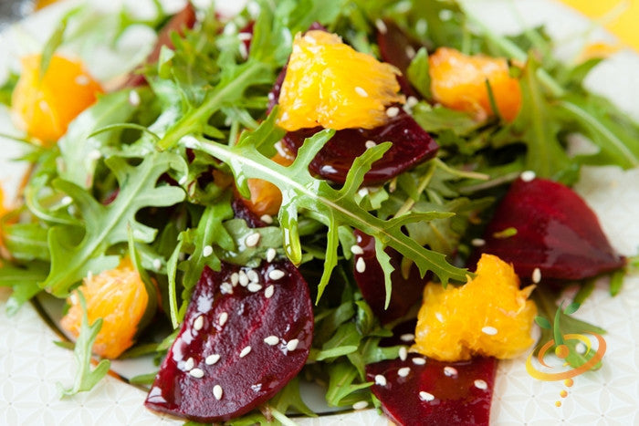 Fresh Bulls Blood beet salad with orange segments and sesame seeds on white plate