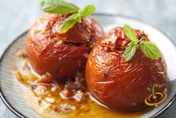Stuffed cooked tomatoes garnished with fresh mint leaves on a plate