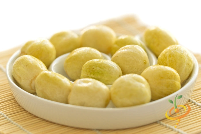 White plate filled with small round yellow lemon cucumbers on a bamboo mat background