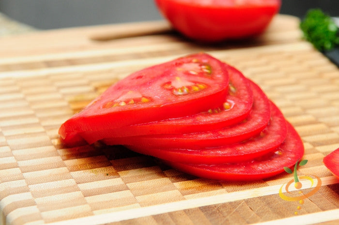 Sliced vibrant red VR Moscow tomato on wooden cutting board with blurred background
