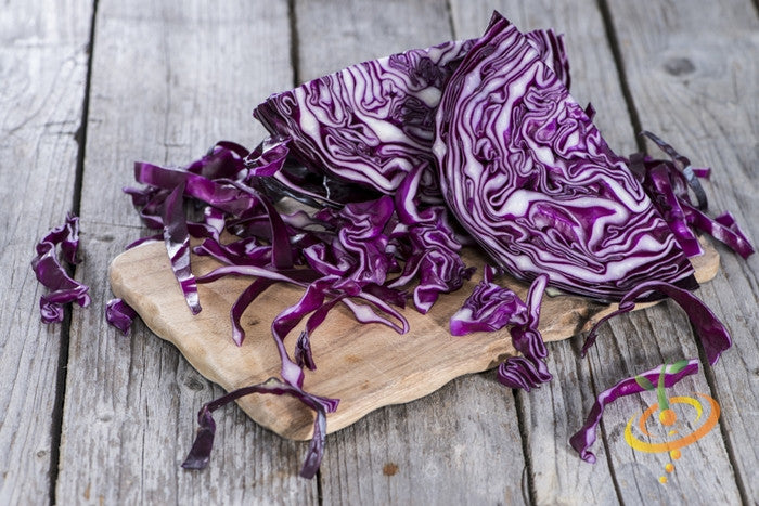 Sliced purple Mammoth Red Rock cabbage on wooden cutting board with rustic background