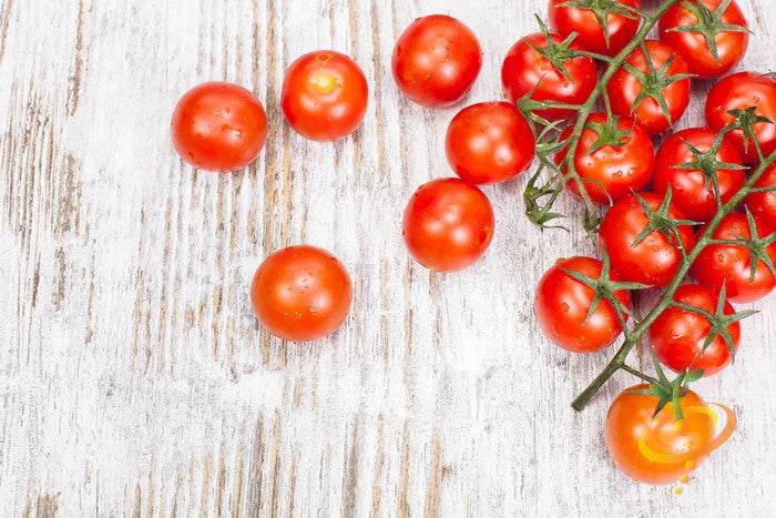 Bright red Tomato Tiny Tim cherry tomatoes on a rustic wooden surface
