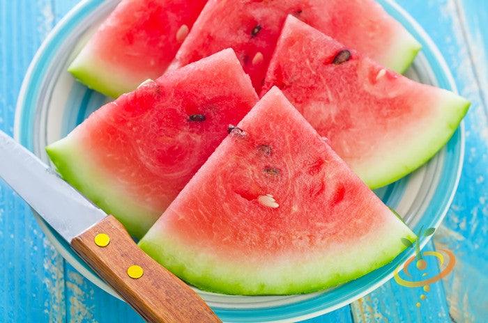 Sliced Florida Giant watermelon pieces with bright red flesh and green rind on a plate with a knife