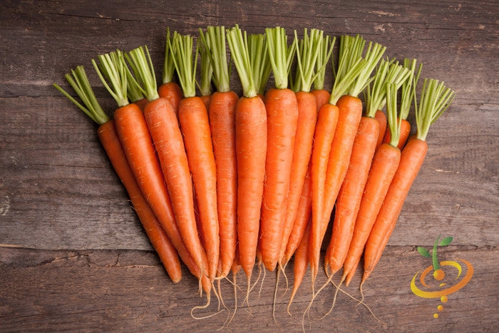 Fresh Tendersweet carrots with green tops arranged on wooden surface