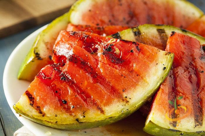 Juicy watermelon grown from Tom Watson seeds, showing vibrant green rind and red flesh with black seeds inside.