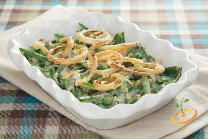 Casserole dish with green bean casserole topped with crispy fried onions on plaid tablecloth