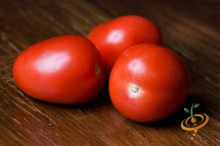 Tomato Roma seeds | Three ripe Roma tomatoes on wooden surface, bright red and smooth-skinned, ideal for sauce making and cooking.