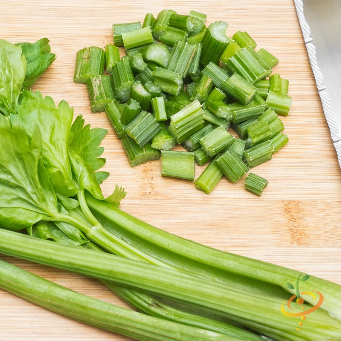 Fresh Tendercrisp celery stalks and chopped celery pieces on wooden cutting board