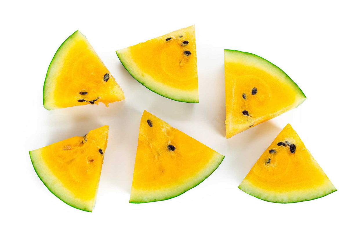 Slices of Watermelon Moon & Stars yellow flesh with dark green rind and black seeds on white background