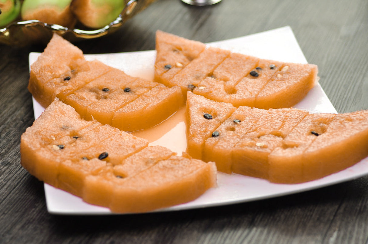 Sliced tender sweet watermelon with bright orange flesh and seeds on a white plate